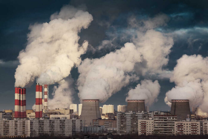 Power,Plant,Smokestacks,Emitting,Smoke,Over,Urban,Cityscape