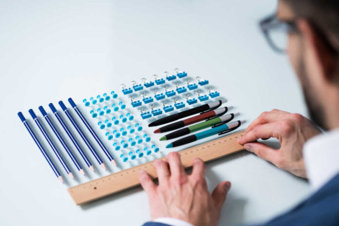 A,Person's,Hand,Arranging,Pencils,And,Multi,Colored,Pushpins,In