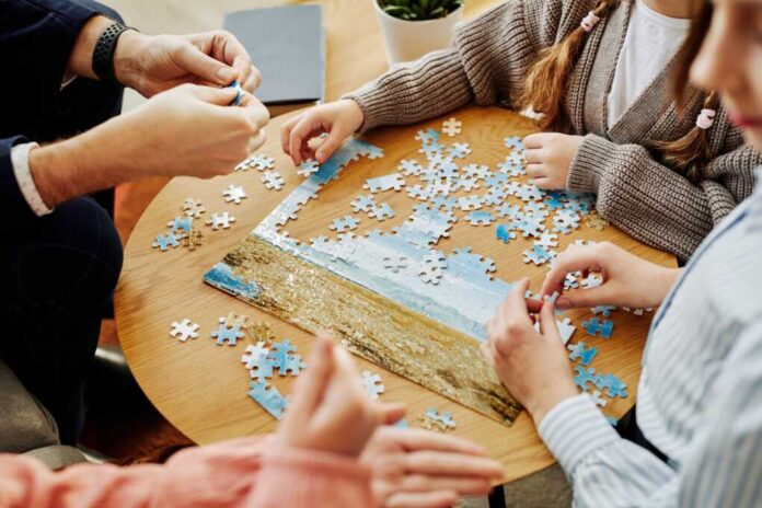 Close,Up,Of,Unrecognizable,Family,Playing,Jigsaw,Puzzle,Game,Together