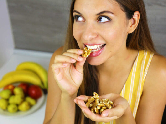 Beautiful,Young,Woman,Smiling,And,Eating,Walnuts,At,Home.,Close