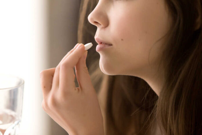Close,Up,Image,Of,Woman,Putting,White,Round,Pill,In