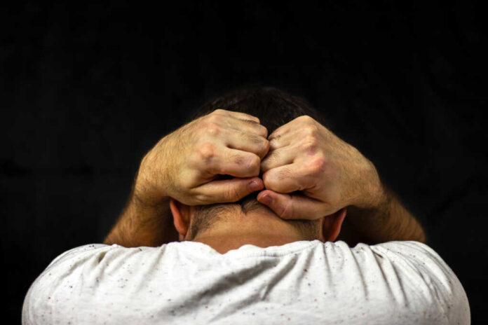 A,Man,In,A,White,T-shirt,Holds,His,Hands,Behind