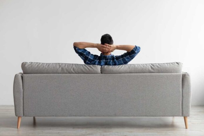 Rear,View,Of,Young,Guy,Sitting,On,Comfortable,Couch,At