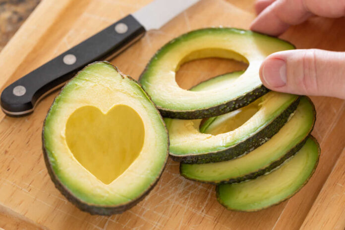 Male,Hand,Prepares,Fresh,Cut,Avocado,With,Heart,Shaped,Pit