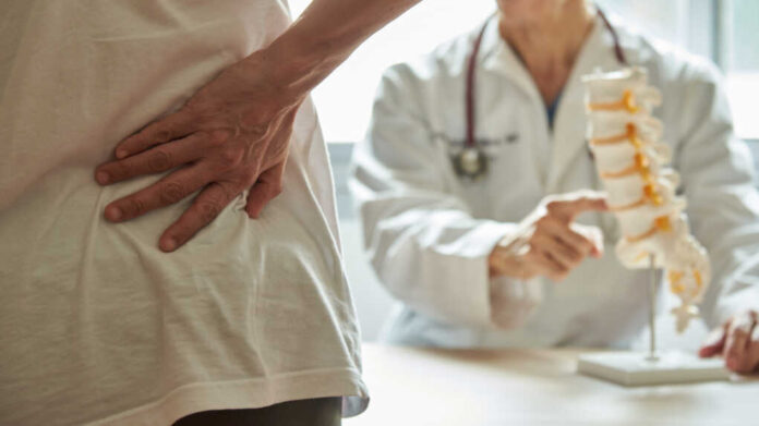 A,Male,Doctor,Explaining,Lumbar,Anatomy,To,Female,Patient,Complaining