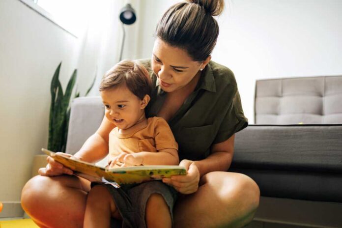 Mom,Reading,A,Book,With,Baby,Boy,At,Home.,Early