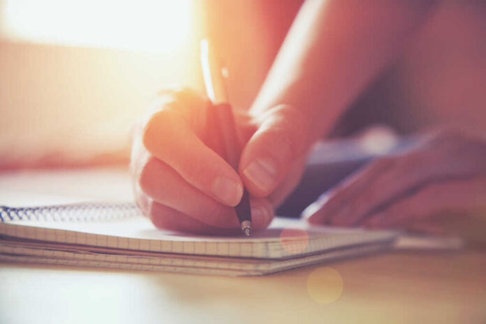 Female,Hands,With,Pen,Writing,On,Notebook